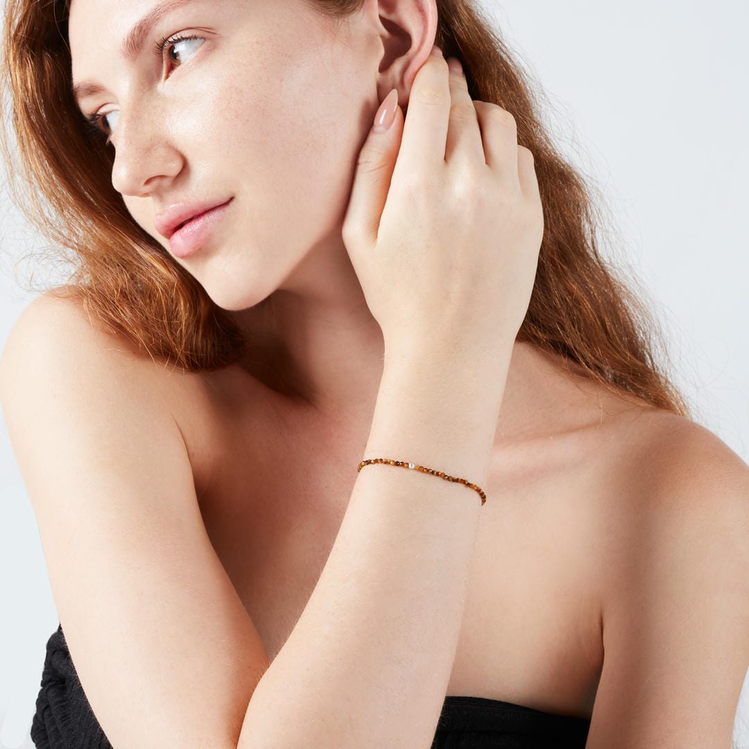Tigerauge Mini-Perlenarmband facettiert mit Silberperle. Frau in Pose, Armband am Handgelenk.